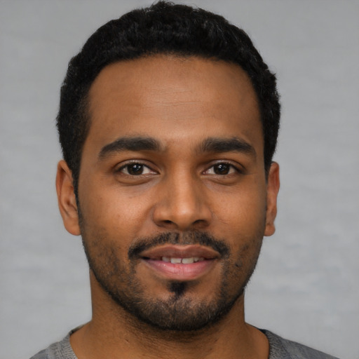 Joyful black young-adult male with short  black hair and brown eyes