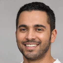 Joyful latino young-adult male with short  black hair and brown eyes