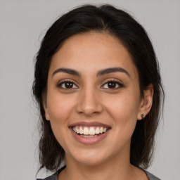 Joyful latino young-adult female with medium  brown hair and brown eyes