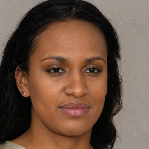 Joyful black young-adult female with long  brown hair and brown eyes