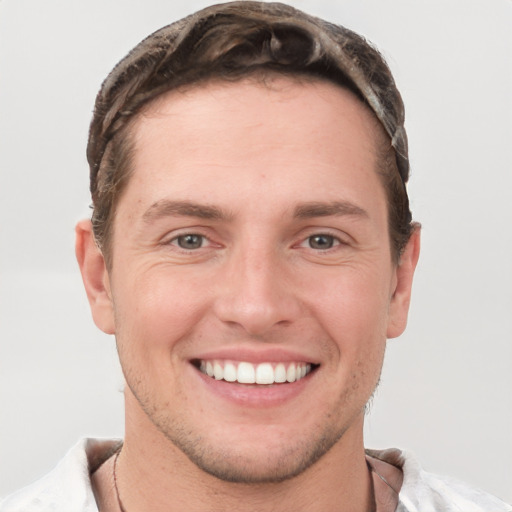 Joyful white young-adult male with short  brown hair and grey eyes