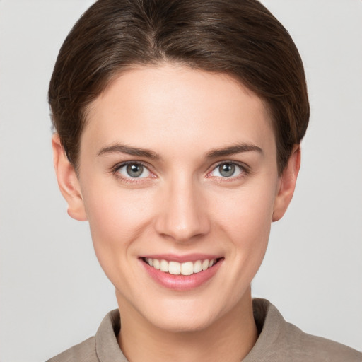 Joyful white young-adult female with short  brown hair and grey eyes