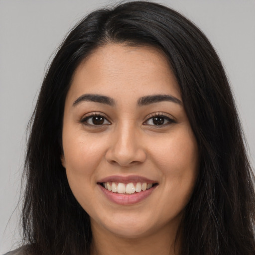 Joyful latino young-adult female with long  brown hair and brown eyes