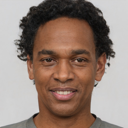 Joyful black adult male with short  black hair and brown eyes
