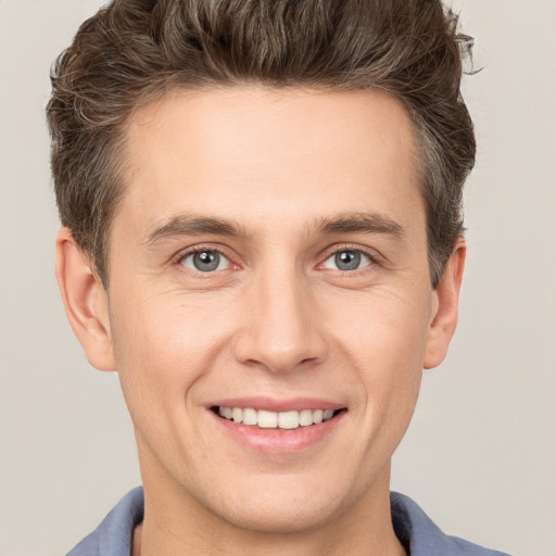 Joyful white young-adult male with short  brown hair and grey eyes