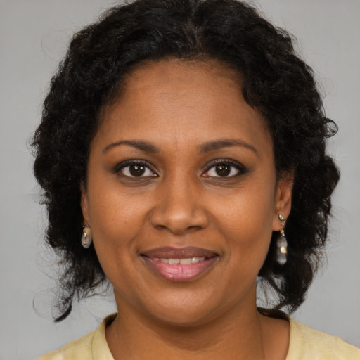 Joyful black young-adult female with long  brown hair and brown eyes
