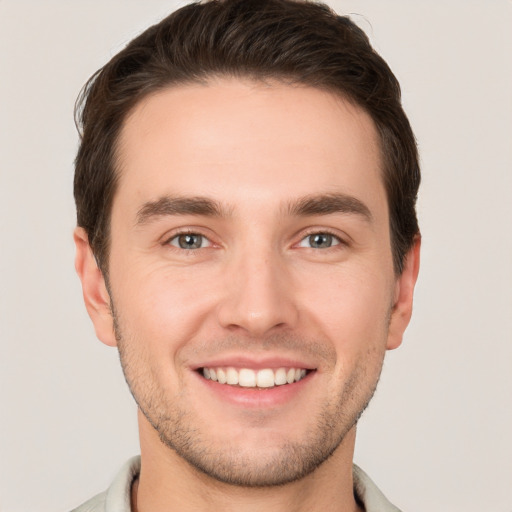 Joyful white young-adult male with short  brown hair and grey eyes