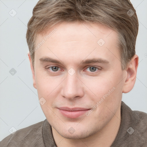 Joyful white young-adult male with short  brown hair and grey eyes