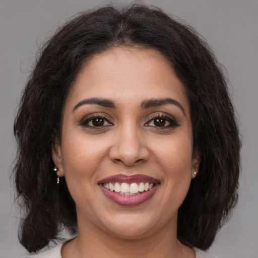 Joyful latino young-adult female with medium  brown hair and brown eyes