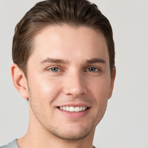 Joyful white young-adult male with short  brown hair and grey eyes