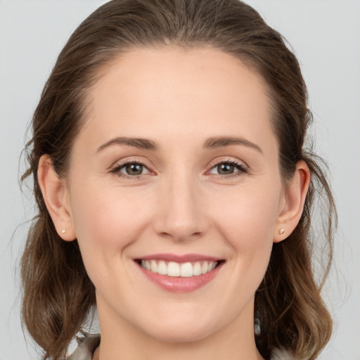 Joyful white young-adult female with medium  brown hair and grey eyes