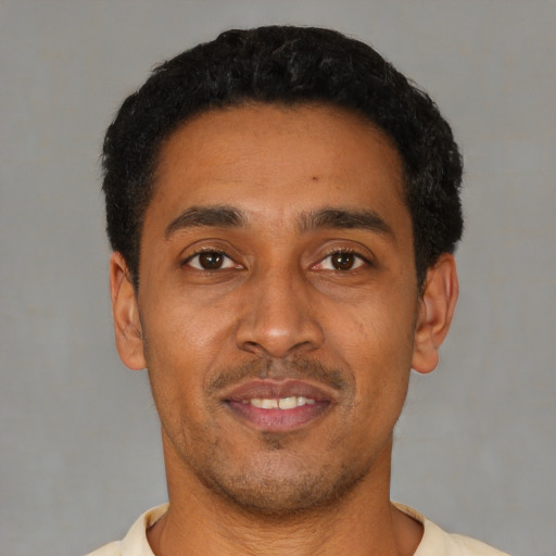 Joyful latino young-adult male with short  black hair and brown eyes