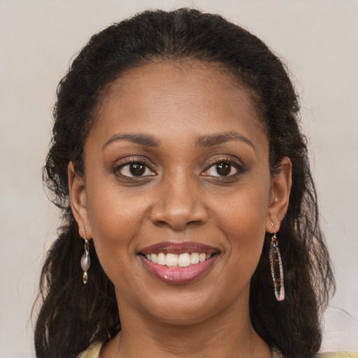 Joyful black young-adult female with long  brown hair and brown eyes