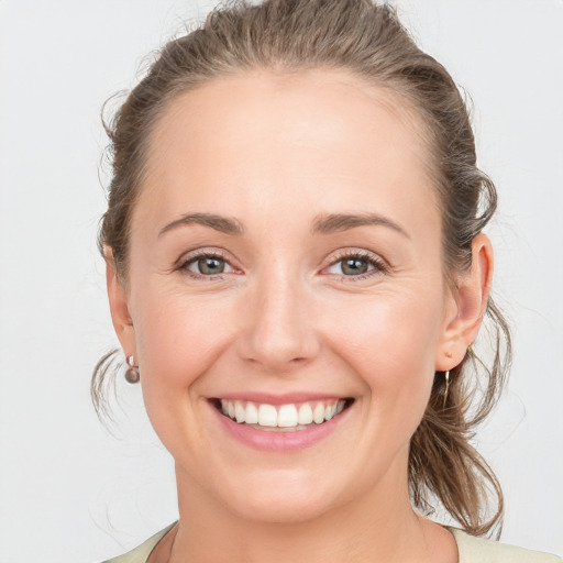 Joyful white young-adult female with medium  brown hair and grey eyes