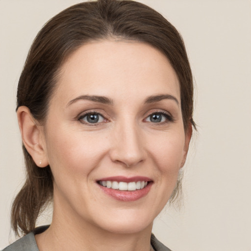 Joyful white young-adult female with medium  brown hair and grey eyes