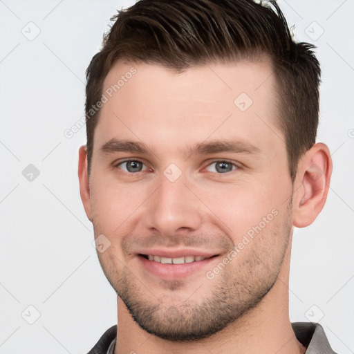 Joyful white young-adult male with short  brown hair and grey eyes