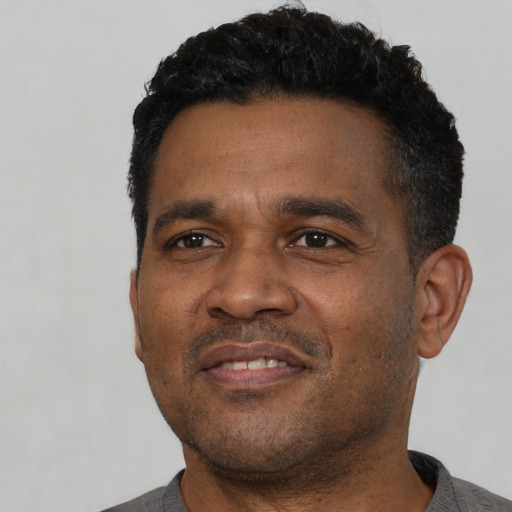 Joyful black young-adult male with short  black hair and brown eyes