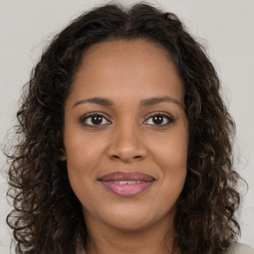 Joyful black young-adult female with long  brown hair and brown eyes
