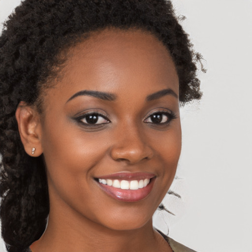 Joyful black young-adult female with long  brown hair and brown eyes