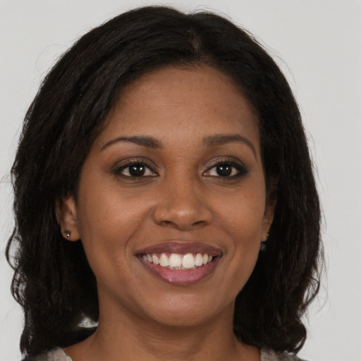 Joyful black young-adult female with long  brown hair and brown eyes