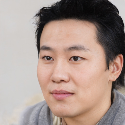 Joyful asian young-adult male with short  black hair and brown eyes