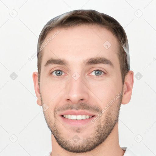 Joyful white young-adult male with short  brown hair and grey eyes