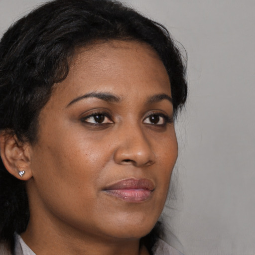 Joyful black young-adult female with long  brown hair and brown eyes