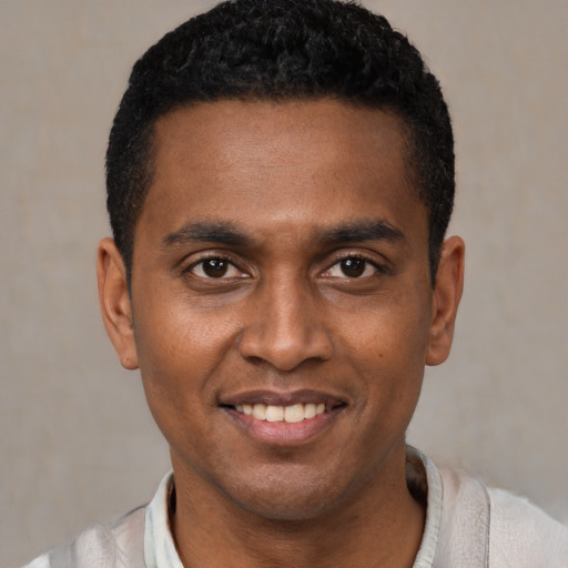 Joyful black young-adult male with short  black hair and brown eyes