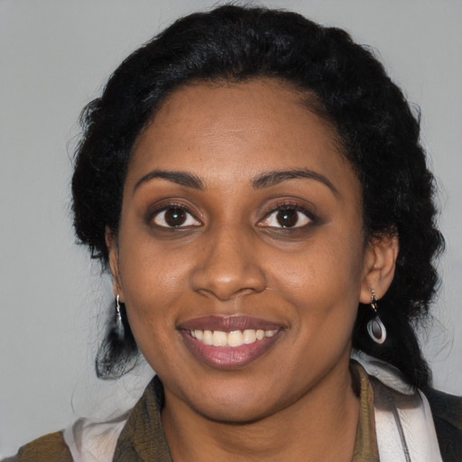 Joyful black young-adult female with long  black hair and brown eyes