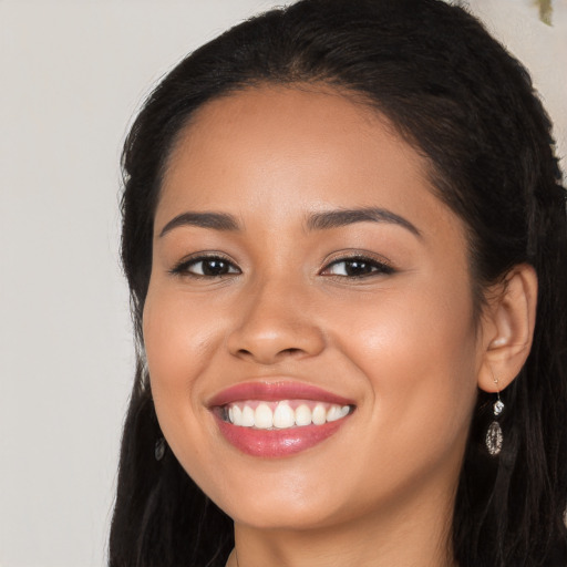 Joyful latino young-adult female with long  black hair and brown eyes