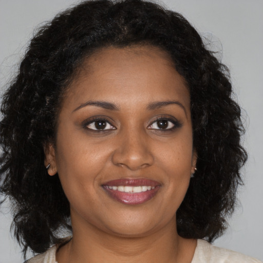 Joyful black young-adult female with long  brown hair and brown eyes