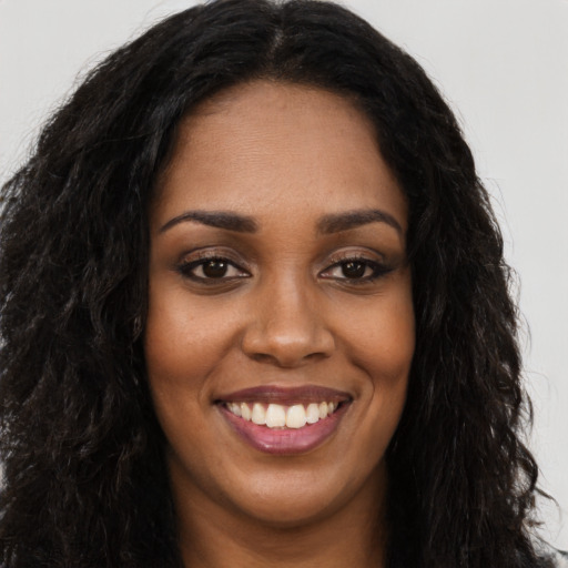Joyful black young-adult female with long  black hair and brown eyes