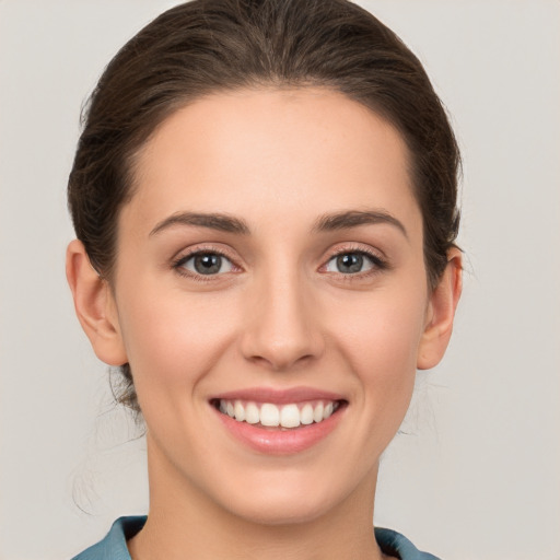 Joyful white young-adult female with medium  brown hair and grey eyes