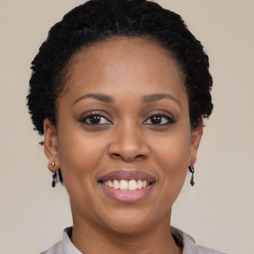 Joyful black young-adult female with short  black hair and brown eyes