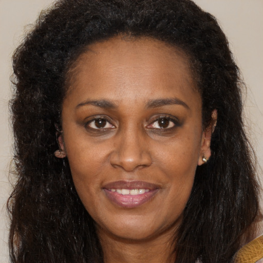 Joyful black young-adult female with long  brown hair and brown eyes