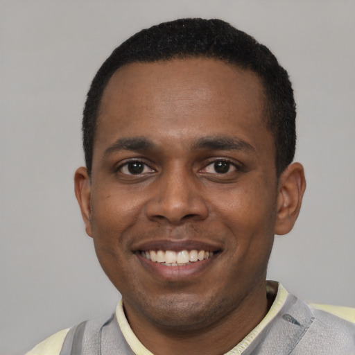 Joyful black young-adult male with short  black hair and brown eyes