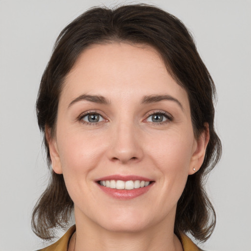 Joyful white young-adult female with medium  brown hair and grey eyes