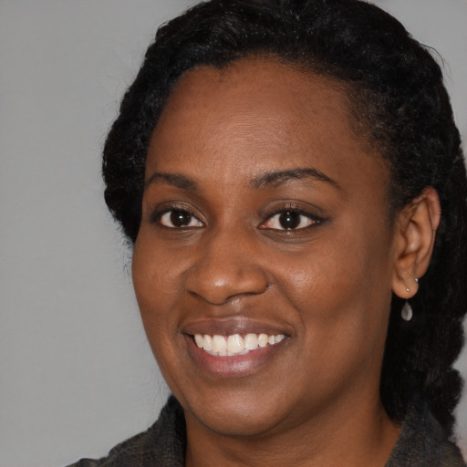 Joyful black young-adult female with long  black hair and brown eyes