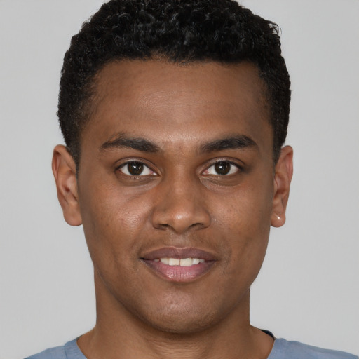 Joyful black young-adult male with short  brown hair and brown eyes