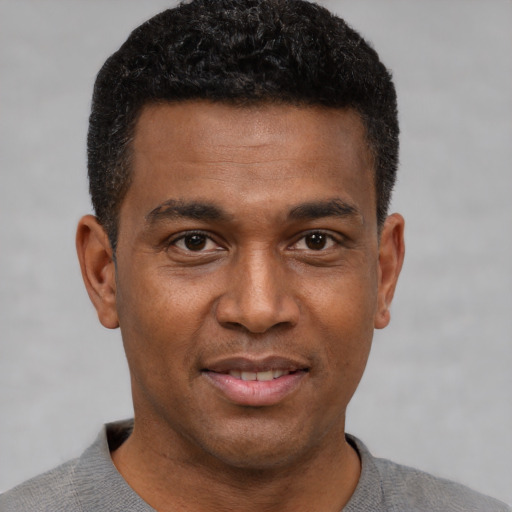 Joyful black young-adult male with short  brown hair and brown eyes