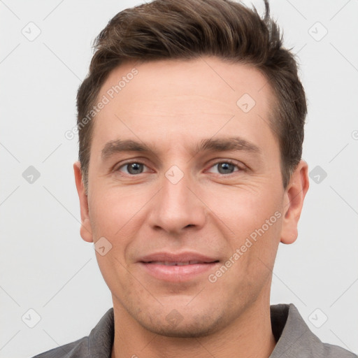 Joyful white young-adult male with short  brown hair and grey eyes