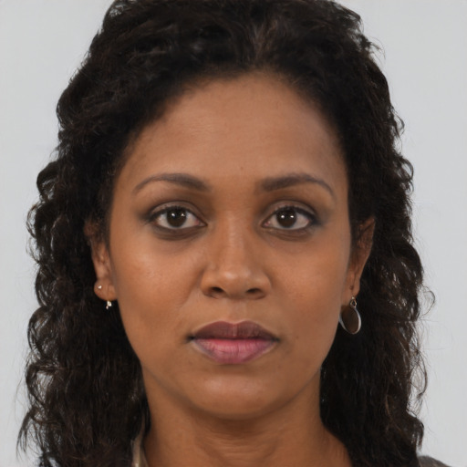 Joyful black adult female with long  brown hair and brown eyes