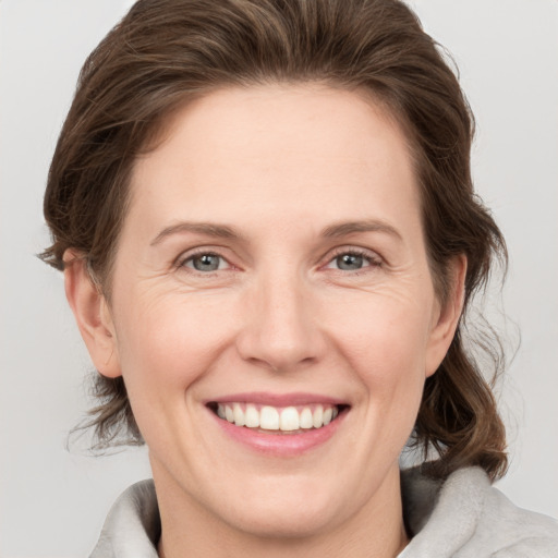 Joyful white young-adult female with medium  brown hair and grey eyes