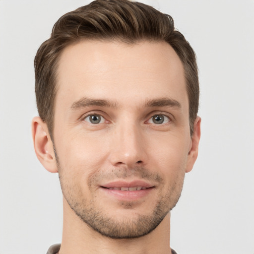 Joyful white young-adult male with short  brown hair and grey eyes