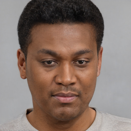 Joyful black young-adult male with short  brown hair and brown eyes