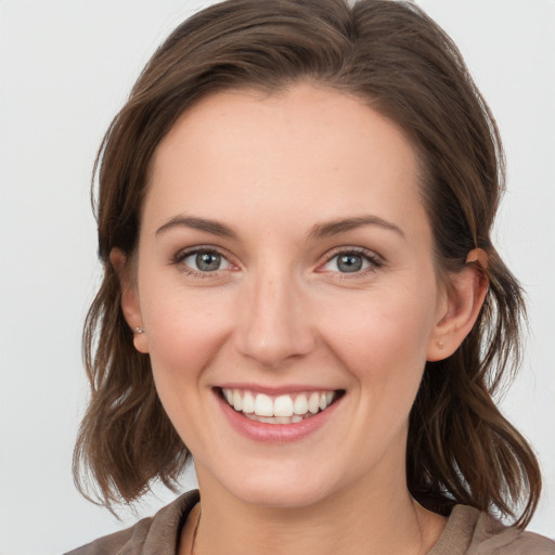 Joyful white young-adult female with medium  brown hair and grey eyes