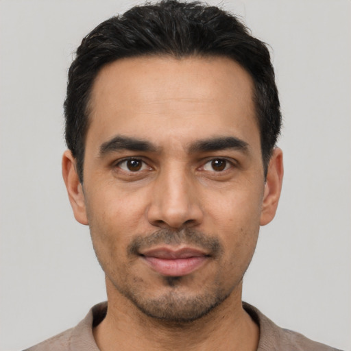 Joyful latino young-adult male with short  black hair and brown eyes