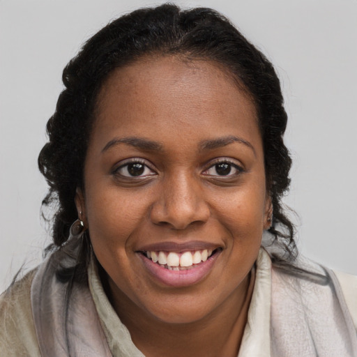 Joyful black young-adult female with long  brown hair and brown eyes