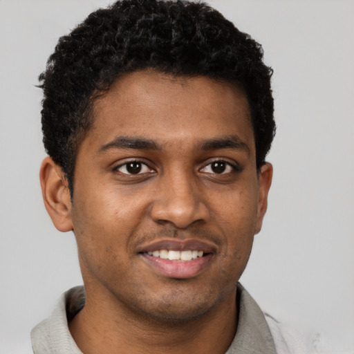 Joyful black young-adult male with short  brown hair and brown eyes