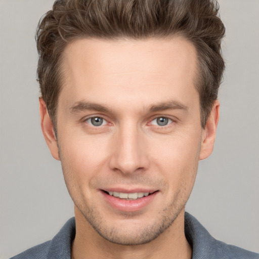 Joyful white young-adult male with short  brown hair and grey eyes